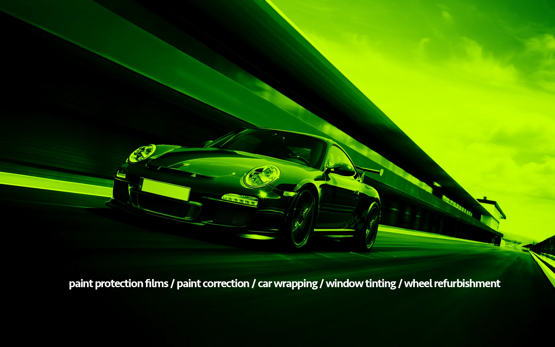 Black Porsche sports car driving along a race track in a green tint, with the words paint protection films, paint correction, car wrapping, window tinting and wheel refurbishment